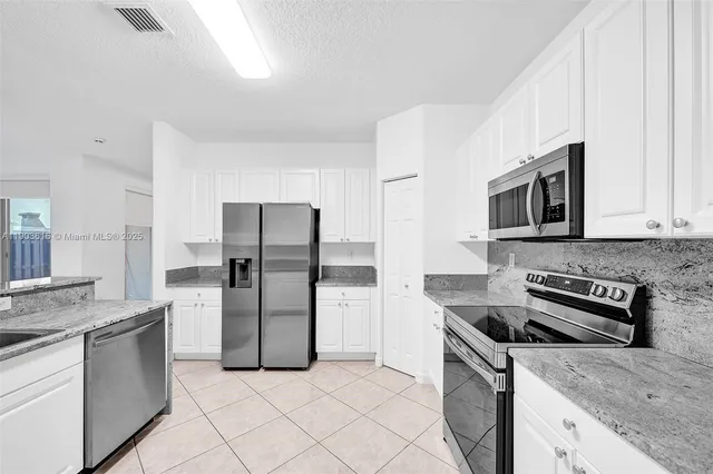 a kitchen with stainless steel appliances granite countertop a refrigerator stove and microwave