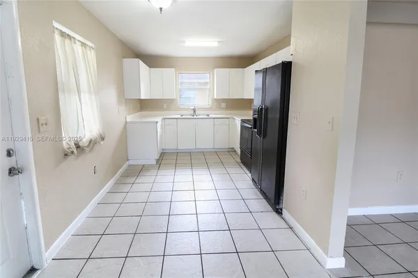a kitchen with white cabinets a sink a window and stainless steel appliances