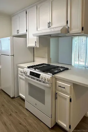 a kitchen with granite countertop white cabinets and white appliances