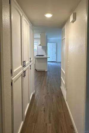 a view of a hallway with wooden floor and cabinets