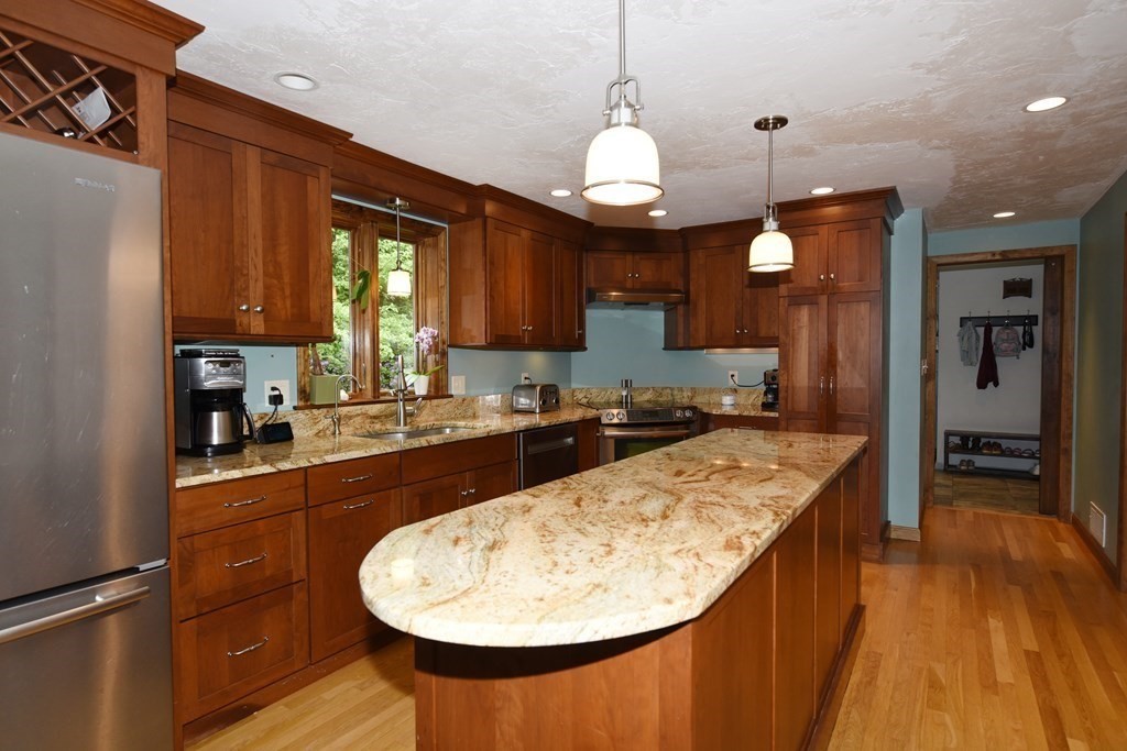 a large kitchen with kitchen island granite countertop wooden cabinets a counter and a sink