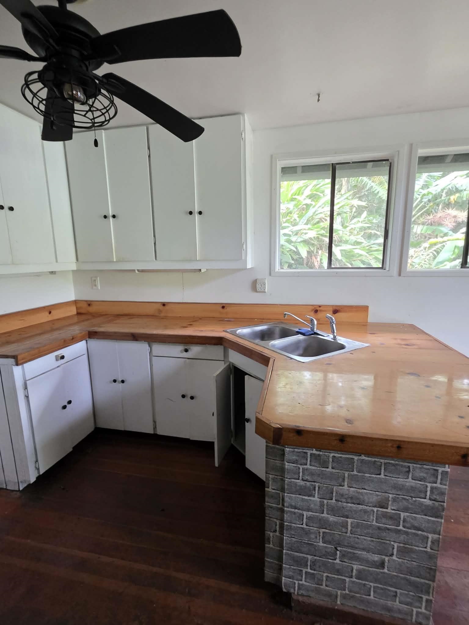 420 Haumana Road Haiku, HI 96708 - Photo 17 of 31 a kitchen with stainless steel appliances granite countertop a sink dishwasher and white cabinets with wooden floor