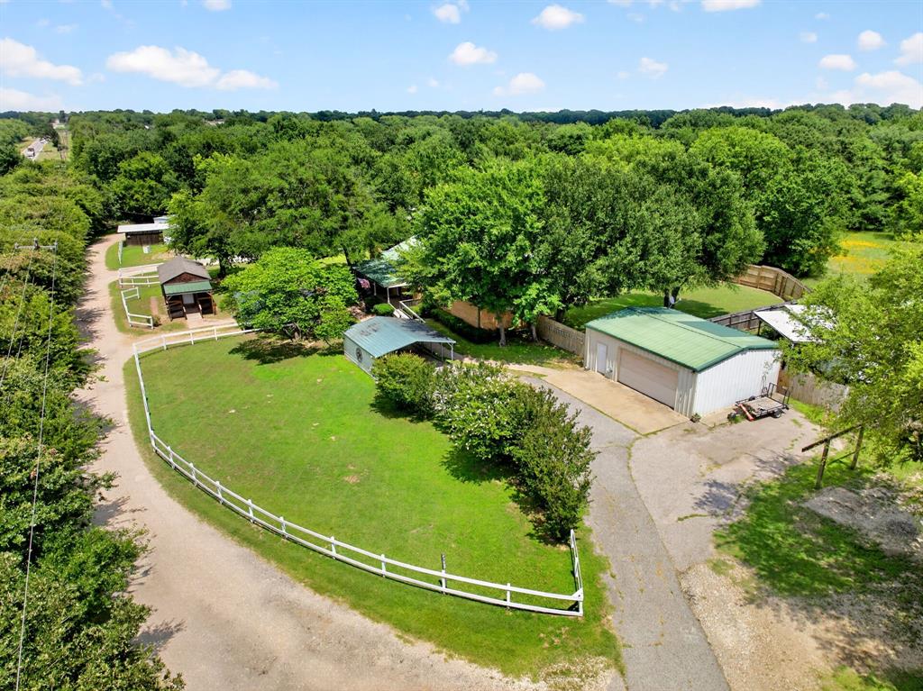 111 County Road 2806 Mabank, TX 75147 - Photo 31 of 34 Spacious property featuring a large metal-sided garage building with a green roof, multiple outbuildings, established trees, and a white fence bordering a grassy area