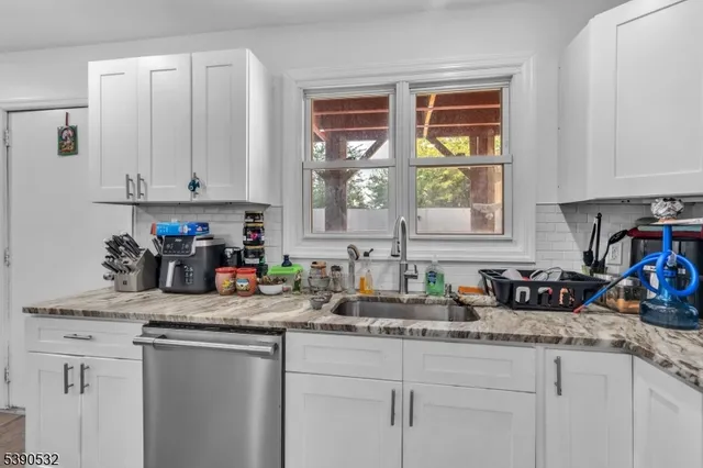a kitchen with stainless steel appliances granite countertop a sink a window and cabinets