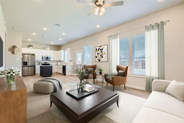 a living room with furniture kitchen view and a large window