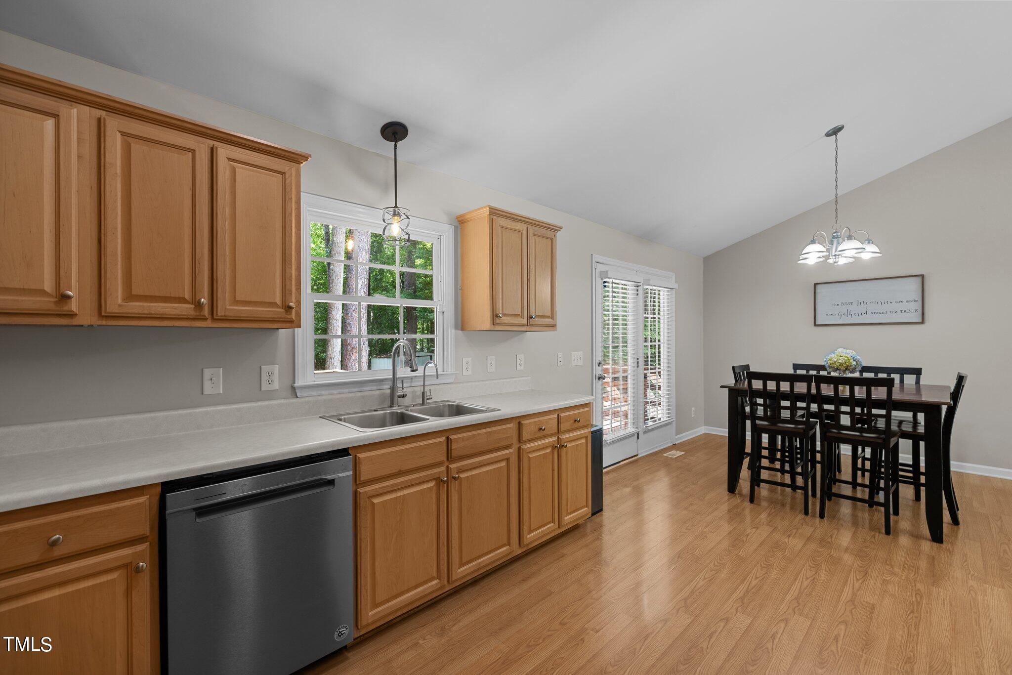 7031 Calais Drive Durham, NC 27712 - Photo 15 of 48 a kitchen with stainless steel appliances granite countertop a sink a stove a dining table and chairs with wooden floor