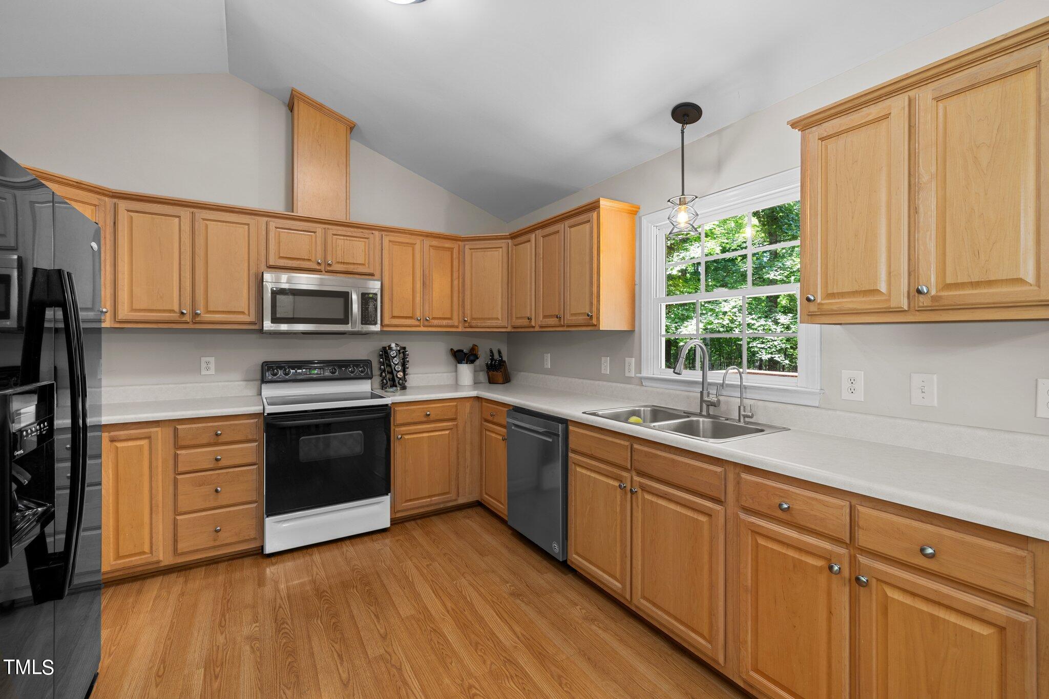 7031 Calais Drive Durham, NC 27712 - Photo 17 of 48 a kitchen with kitchen island granite countertop a sink cabinets stainless steel appliances and a window