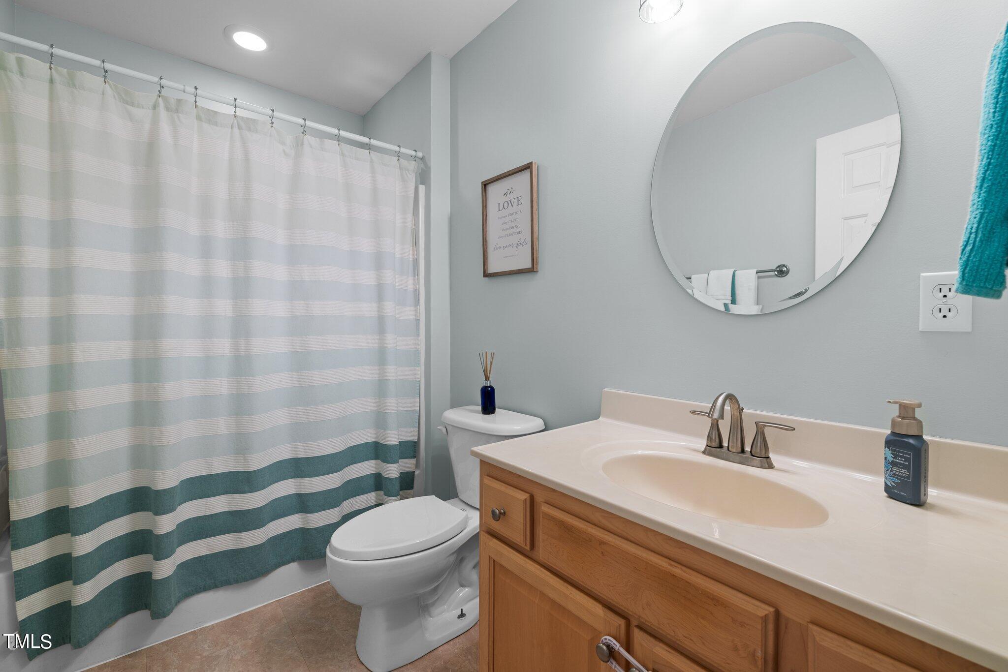 7031 Calais Drive Durham, NC 27712 - Photo 25 of 48 a bathroom with a sink a toilet and shower curtain