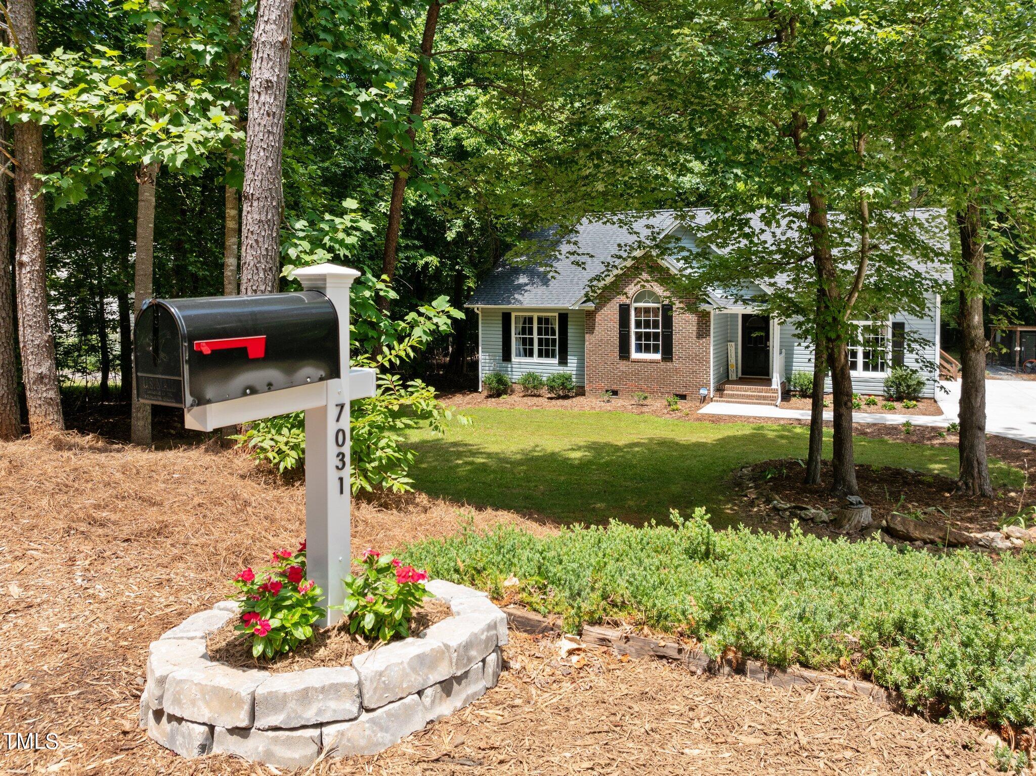 7031 Calais Drive Durham, NC 27712 - Photo 43 of 48 a front view of a house with a yard fountain and tree