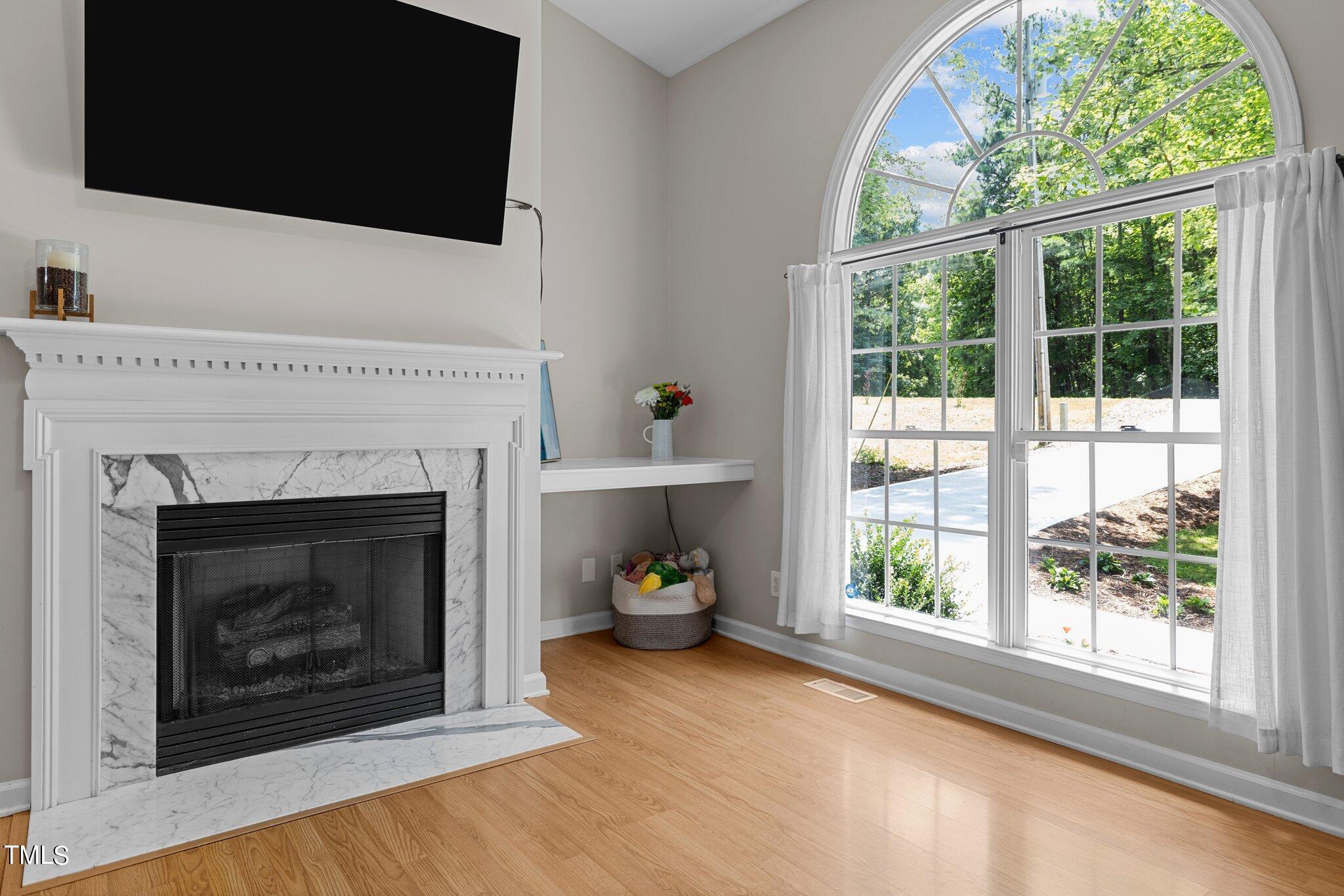 7031 Calais Drive Durham, NC 27712 - Photo 6 of 48 a living room with a fireplace and a flat screen tv