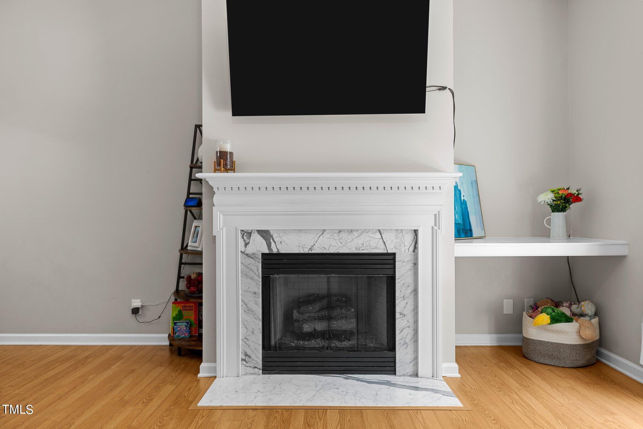7031 Calais Drive Durham, NC 27712 - Photo 7 of 48 a living room with a fireplace wooden floor and a flat screen tv