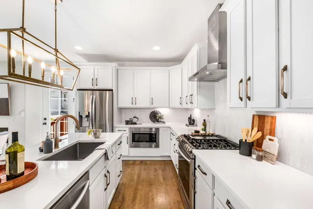 a kitchen that has a lot of white cabinets and stainless steel appliances