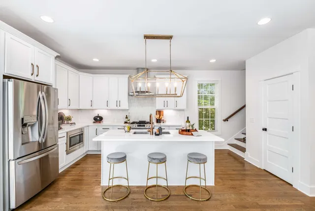 a kitchen with stainless steel appliances a dining table chairs sink and refrigerator