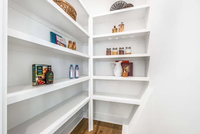 a view of kitchen cabinets with food items with white countertops and wooden floor