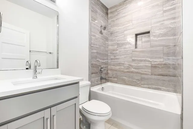 a bathroom with a bathtub shower sink vanity mirror and toilet