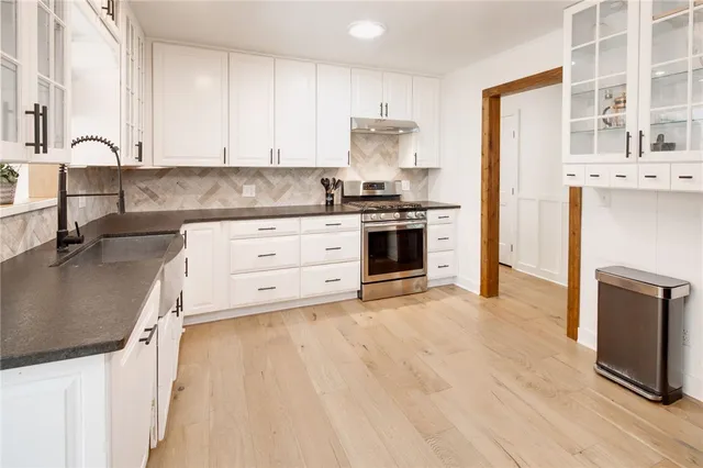 a kitchen with granite countertop a stove a sink and a refrigerator