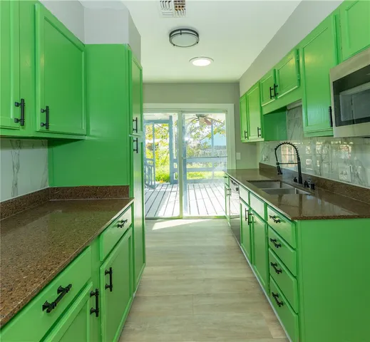 a kitchen with green cabinets a sink and a dishwasher