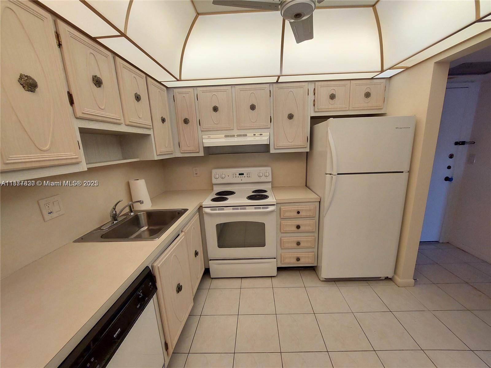 257 South Cypress Road, Unit 438 Pompano Beach, FL 33060 - Photo 3 of 20 a kitchen with white cabinets and white appliances