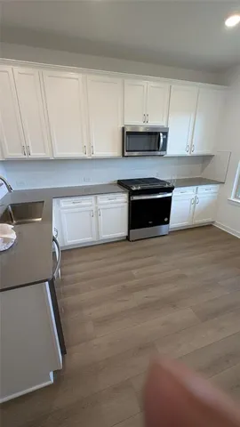 a kitchen with granite countertop a stove and white cabinets