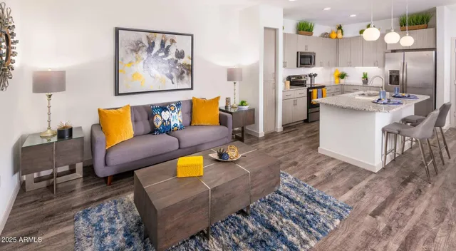 a living room with stainless steel appliances furniture and a kitchen view