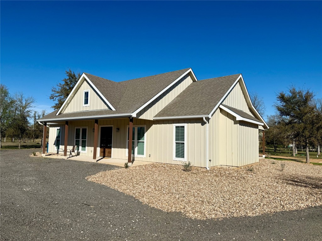 Modern inspired farmhouse with a shingled roof, covered porch, and board and batten siding