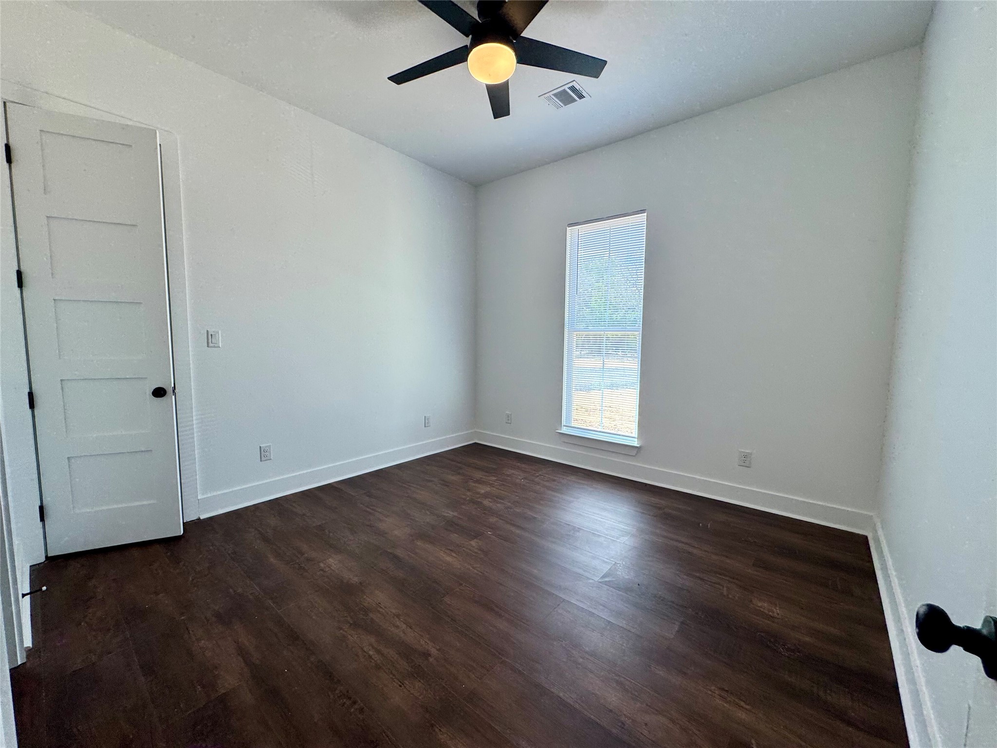 1353 Red Town Road, Unit B Elgin, TX 78621 - Photo 23 of 26 an empty room with wooden floor chandelier fan and windows