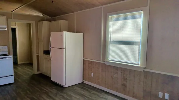 a view of a kitchen with wooden floor and a refrigerator