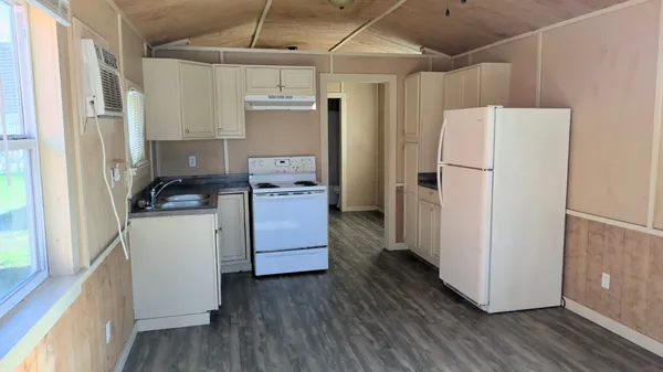 a kitchen with refrigerator a stove and white cabinets with wooden floor