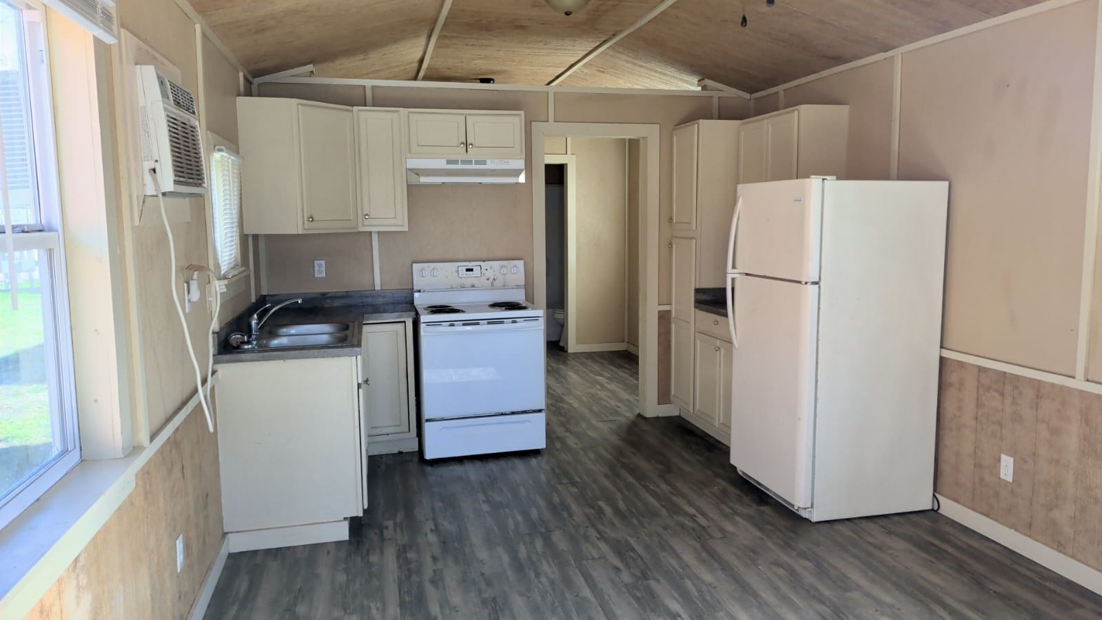 401 North Clegg Street Trinity, TX 75862 - Photo 7 of 15 a kitchen with refrigerator a stove and white cabinets with wooden floor