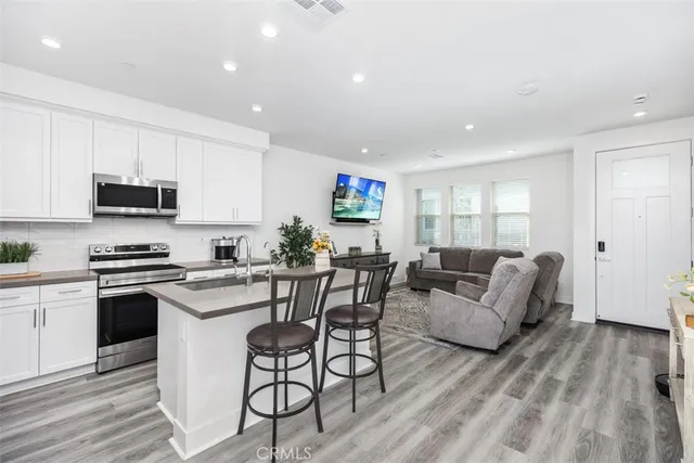 a living room with furniture a rug kitchen view and a window