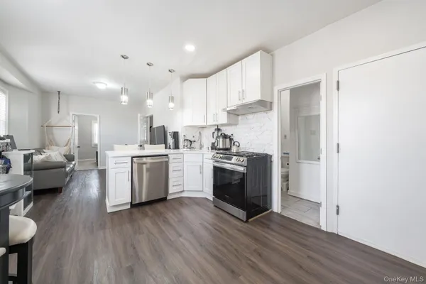 a kitchen with a sink a stove a refrigerator and white cabinets with wooden floor