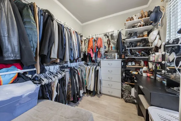 a view of walk in closet with clothes and shoes