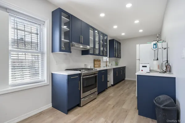 a large kitchen with stainless steel appliances granite countertop a stove a sink and a large window