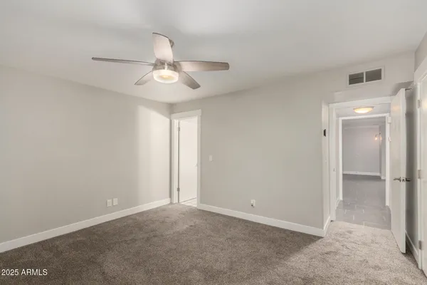 an empty room with a window and ceiling fan