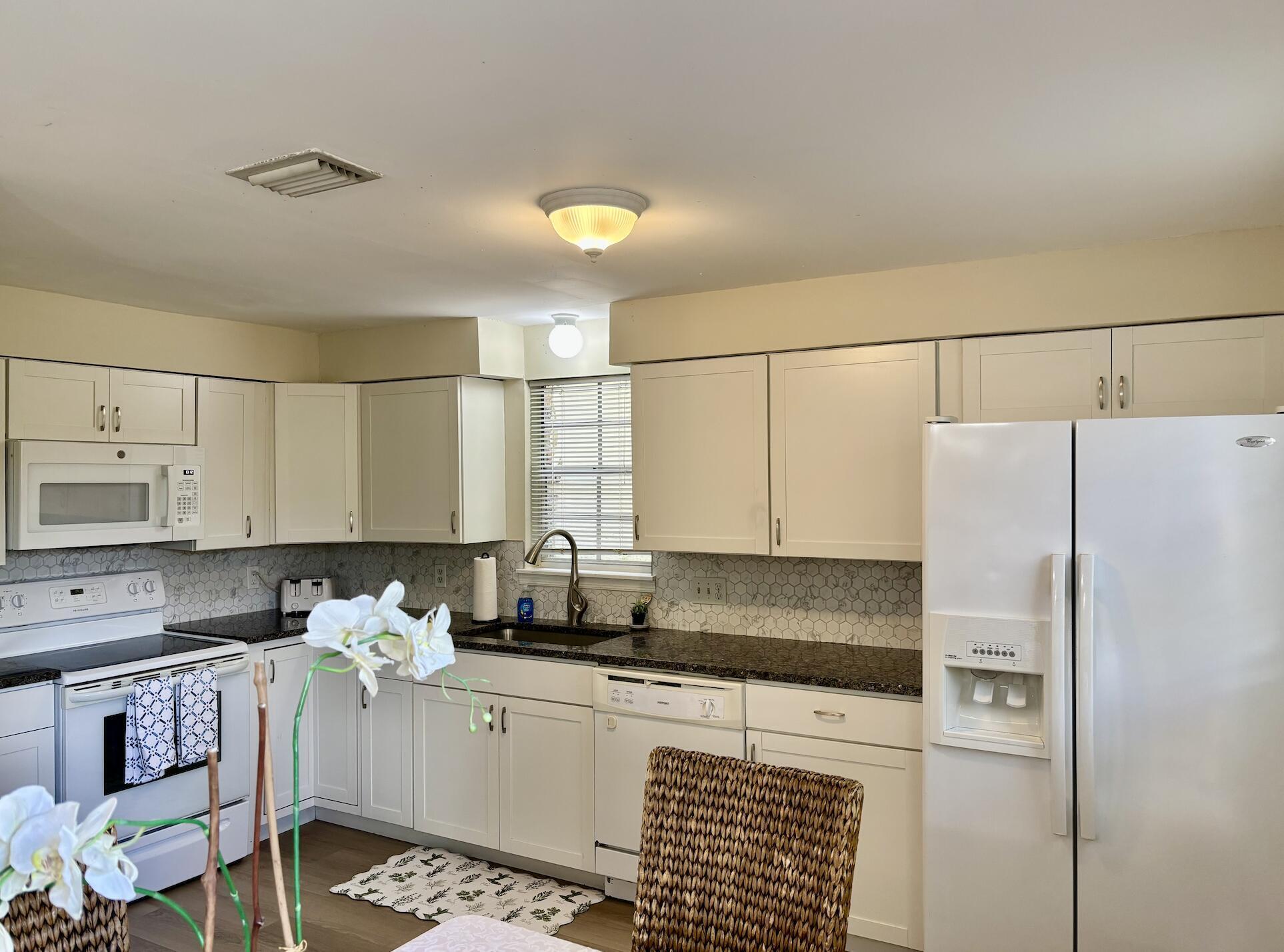 13472 Old Englishtown Road Wellington, FL 33414 - Photo 8 of 18 a kitchen with stainless steel appliances granite countertop a refrigerator sink stove and white cabinets