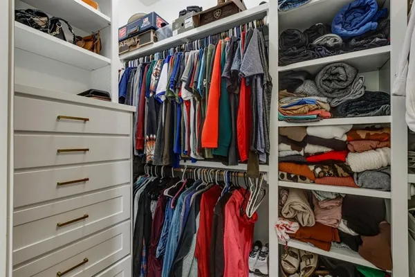 a view of walk in closet with clothes and shoes
