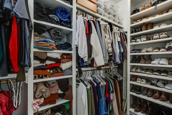 a view of walk in closet with clothes and shoes