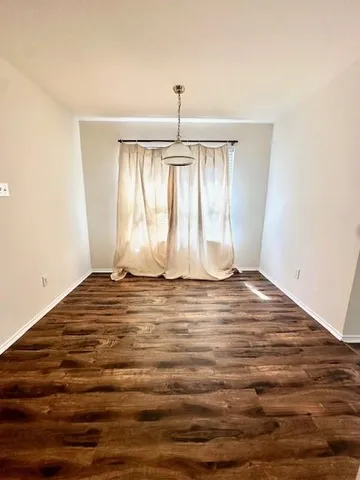 a view of empty room with window and wooden floor