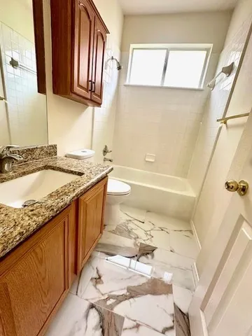 a bathroom with a granite countertop sink a toilet and bathtub