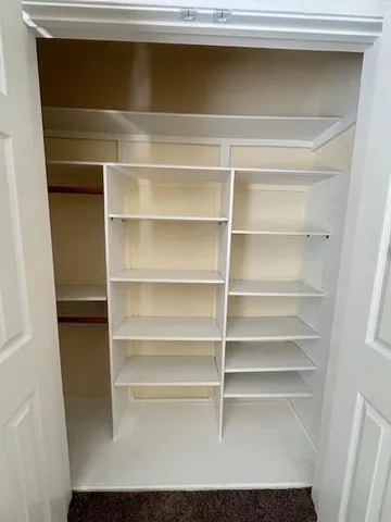 a view of walk in closet with empty racks