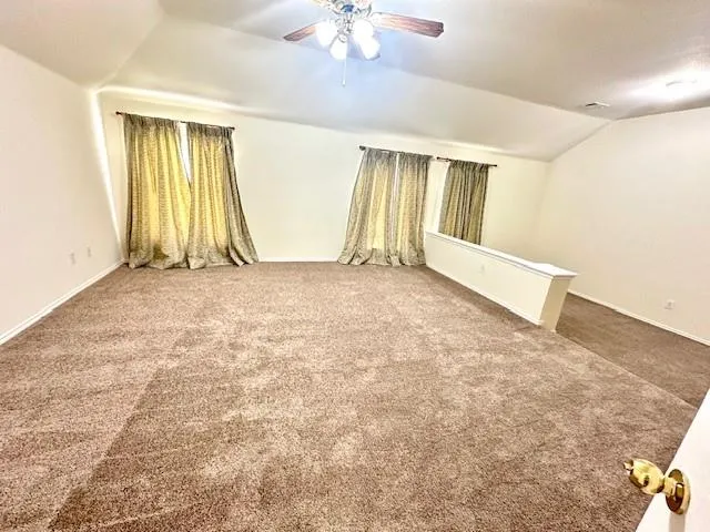 an empty room with windows and a chandelier fan