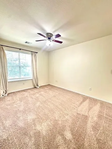 an empty room with chandelier fan and windows