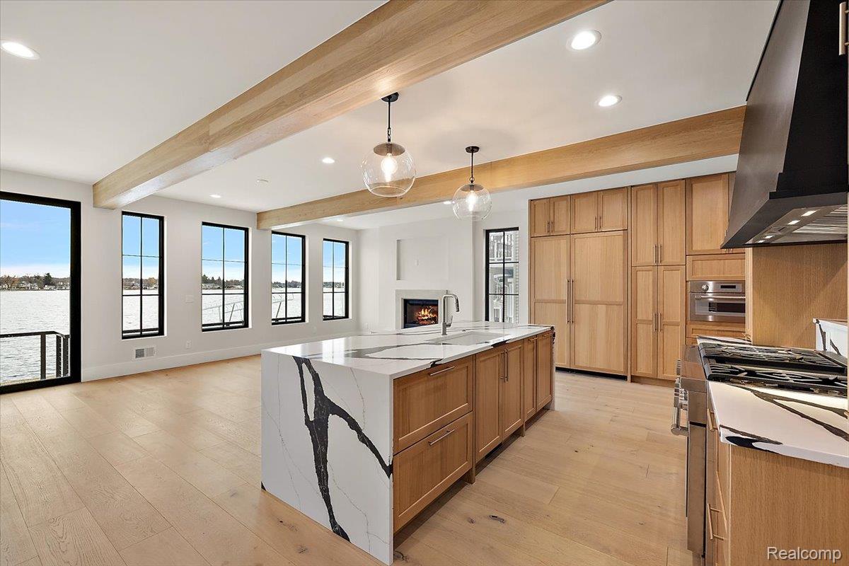 13459 Haddon Street Fenton, MI 48430 - Photo 79 of 84 Kitchen featuring open floor plan, light stone counters, an island with sink, stainless steel appliances, and beamed ceiling