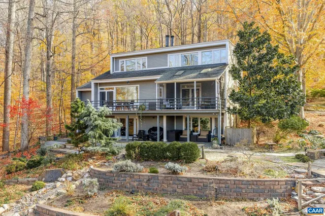 a view of a white house next to a yard with large trees