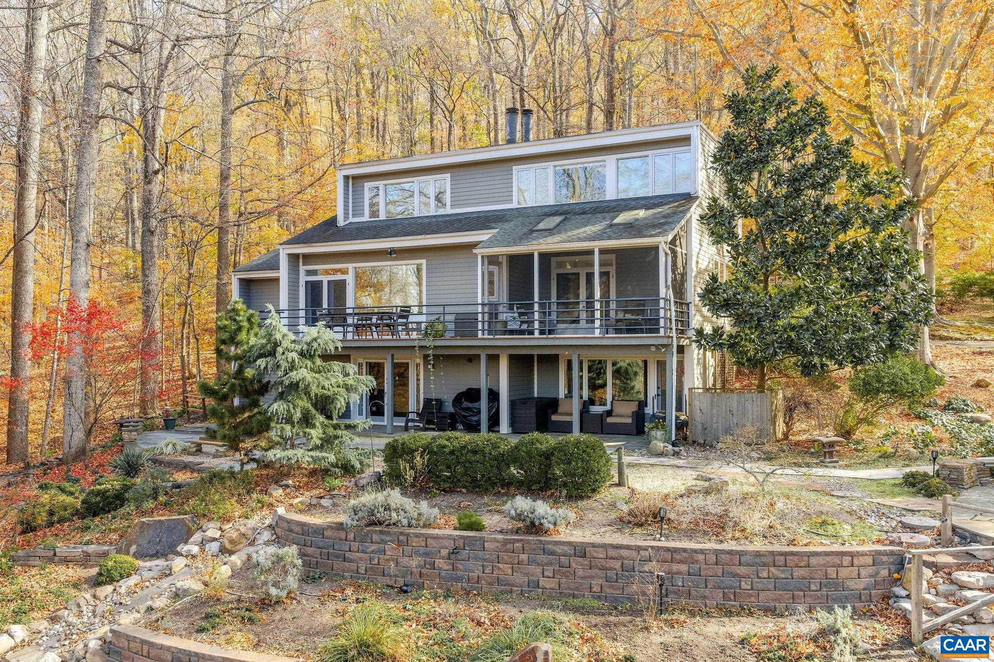 a view of a white house next to a yard with large trees