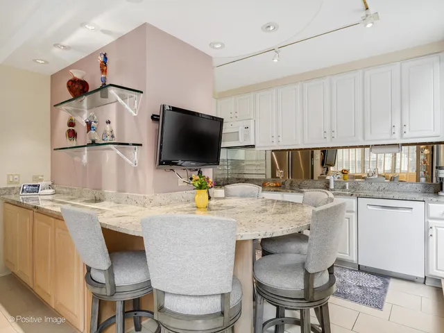 a kitchen with stainless steel appliances a stove a sink a microwave a dining table and chairs