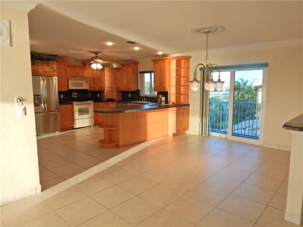 1201 South Riverside Drive, Unit PHB Pompano Beach, FL 33062 - Photo 13 of 33 a open kitchen with stainless steel appliances granite countertop a refrigerator a sink a stove and oven with wooden floor