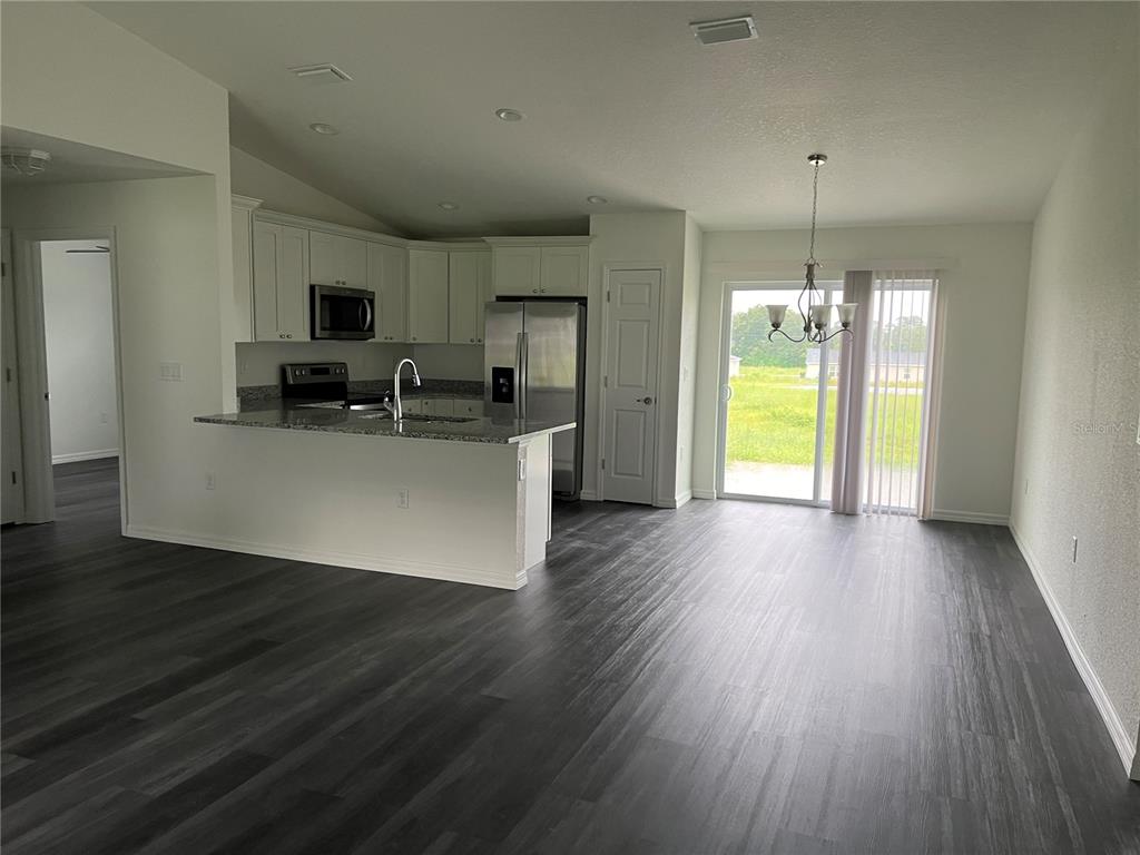 9 Maple Lane Ocklawaha, FL 32179 - Photo 4 of 26 a view of a kitchen with a flat screen tv a refrigerator and a floor to ceiling window