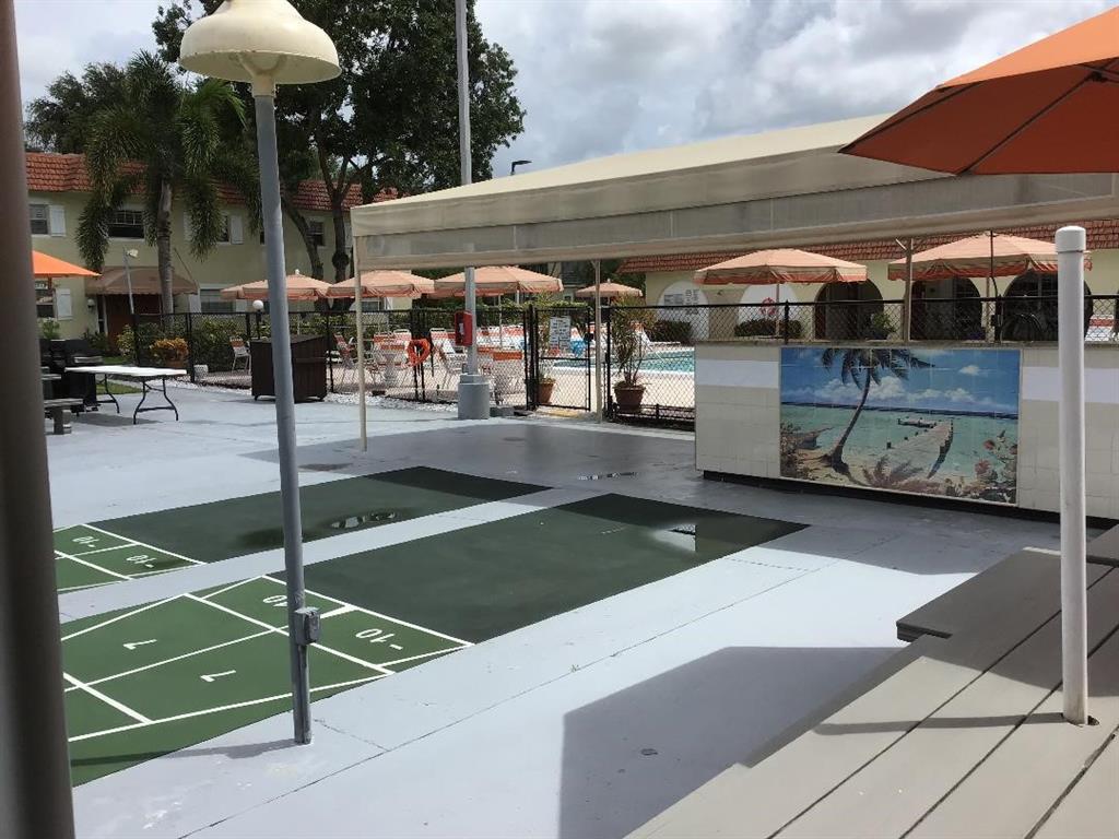 5641 Southwest 2nd Court, Unit 212 Margate, FL 33068 - Photo 14 of 18 a view of a patio with table and chairs under an umbrella