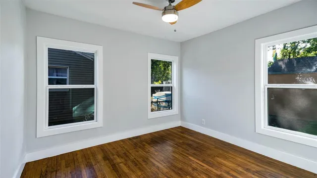 a view of an empty room with a window and wooden floor